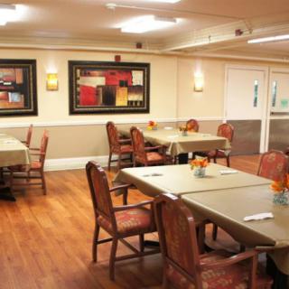 A cozy dining area with neatly arranged tables and chairs, adorned with colorful artwork on the walls.