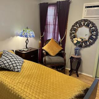 A cozy bedroom featuring a warm yellow bedspread, stylish furniture, and decorative accents.
