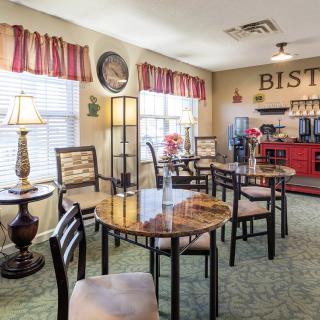 A cozy indoor bistro with multiple tables and chairs, decorated with elegant lamps and curtains.
