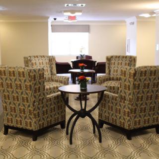 A cozy lounge area with patterned armchairs and small tables arranged in a welcoming setup.