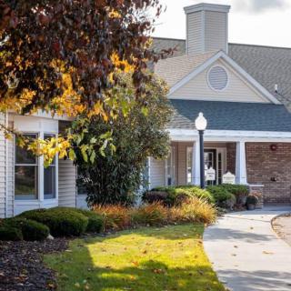 A charming building surrounded by autumn foliage and a winding pathway in the sunlight.