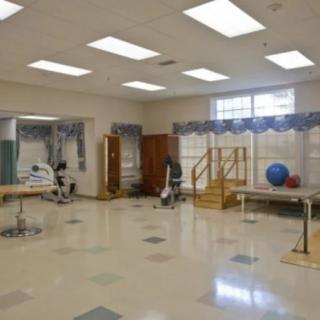 A spacious physical therapy room equipped with rehabilitation tools such as exercise balls, parallel bars, and stairs.