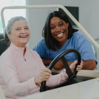 A nurse assists a patient in a therapeutic driving simulation.