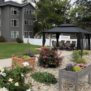 A beautiful garden with raised flower beds and a gazebo next to an apartment building.