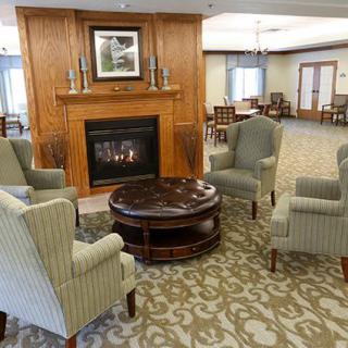 A cozy living room setup with four chairs around a wooden coffee table in front of a fireplace.