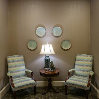 A cozy seating area with striped chairs and a lamp, adorned by decorative plates on the wall.