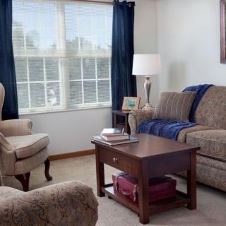 Cozy living room with sofa, armchair, and coffee table near a large window.