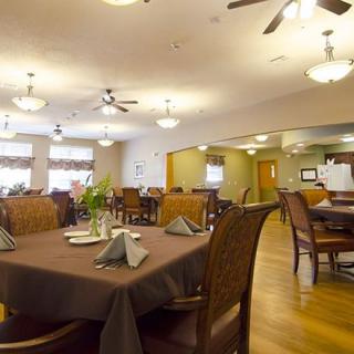 A cozy dining room with neatly arranged tables and chairs, under warm lighting.