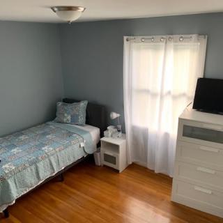 A minimalist bedroom with a single bed, nightstand, and chest of drawers.