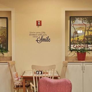 A cozy dining area with a small table set, wall art, and plants, featuring an inspirational quote.
