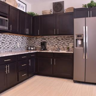 A modern kitchen with dark cabinetry, stainless steel appliances, and a stylish backsplash.