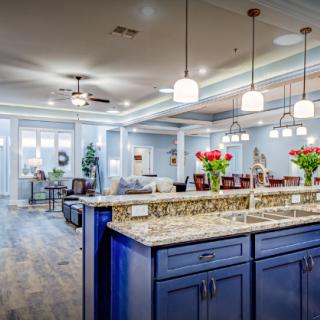 Modern kitchen with blue cabinets and granite countertops extending into a spacious open living area.