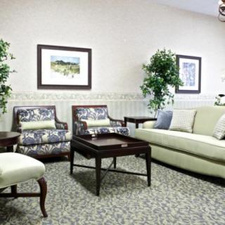A cozy living room with elegant furniture, including a sofa and chairs, complemented by indoor plants and wall art.