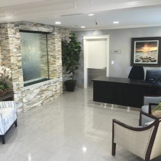A modern office waiting room featuring sleek furniture and a calming water feature.