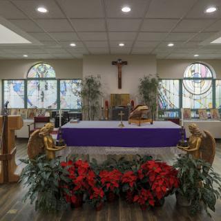 A serene interior of a church featuring a beautifully adorned altar with floral arrangements and stained glass windows.
