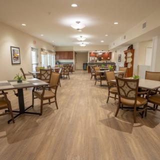 A spacious dining area with tables and chairs arranged neatly on a wooden floor.