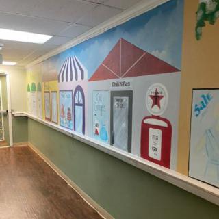 A colorful mural depicting various buildings decorates a hallway.