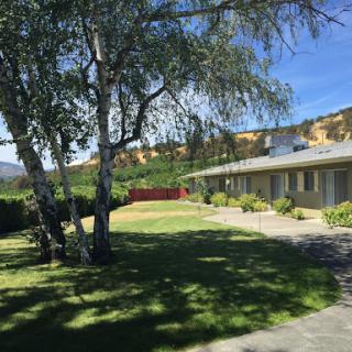 A serene view of a house surrounded by lush greenery and blue skies.