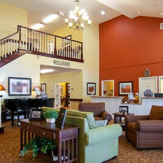 A welcoming hotel lobby featuring comfortable seating, a staircase, and decorative artwork.
