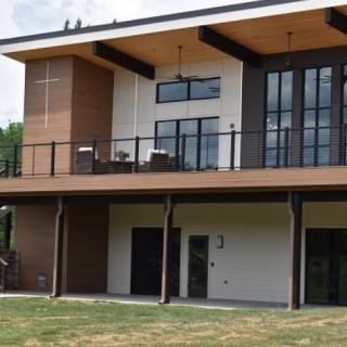 A modern two-story house with a spacious balcony and large windows.