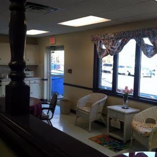 A cozy waiting area with chairs and a table near large windows.