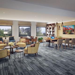 A modern lounge with comfortable seating, large windows, and a cozy reading area equipped with bookshelves.