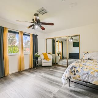 A modern bedroom featuring mirrored closet doors, a ceiling fan, and stylish decor with hardwood flooring.