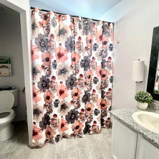 A stylish bathroom featuring a floral shower curtain and modern fixtures.