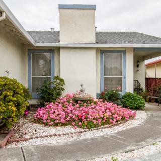 A charming house with a well-maintained front yard featuring a flower garden and a driveway.