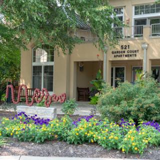 The welcoming entrance of a beautifully landscaped apartment complex.