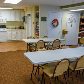 A community space with tables and chairs near a kitchen area.