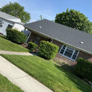 A suburban house with a well-maintained lawn and sidewalk on a sunny day.