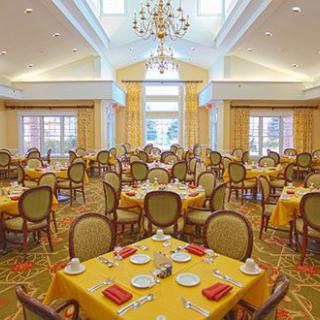An elegant dining room with neatly set tables and a chandelier overhead.