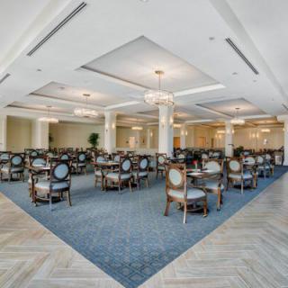 A spacious and elegant dining area with neatly arranged tables and chairs, complemented by sophisticated lighting.