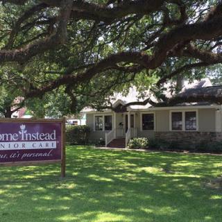 A welcoming home-like facility with a prominent sign under a sprawling tree.