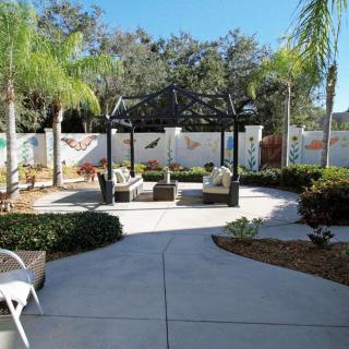 A peaceful outdoor patio area with comfortable seating surrounded by palm trees and landscaped gardens.