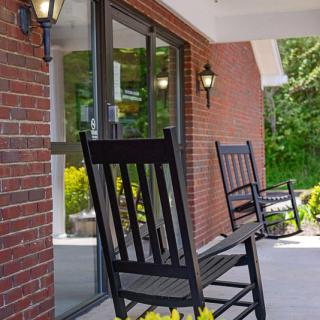 A cozy porch with black rocking chairs and brick walls.