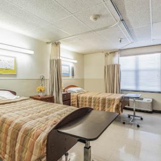 A well-lit hospital patient room featuring two beds and a modern design.