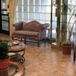 A cozy indoor area featuring a sofa, glass wall, potted plants, and a round table.