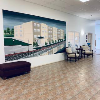 A lobby area featuring chairs and a mural depicting a building.