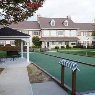 A residential building with a bocce court and gazebo in the foreground.