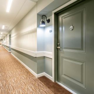 A well-lit hotel hallway with a carpeted floor and numbered doors.