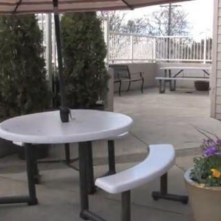 An outdoor patio area with a round table, bench seating, and potted plants.