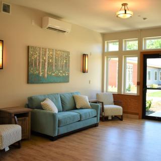 A bright and airy living room with a comfortable couch, modern artwork, and large windows letting in natural light.