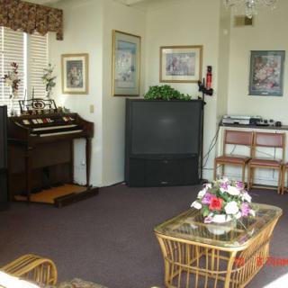 A cozy living room with a vintage organ, television, and floral decor.