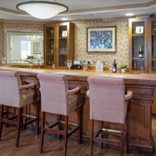 A cozy bar interior featuring wooden furniture and wine bottles.