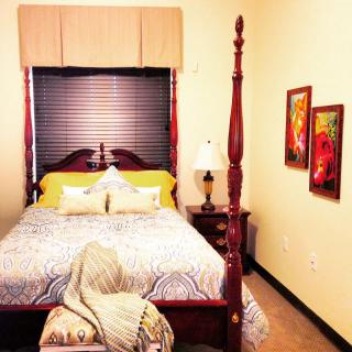 A cozy bedroom with a four-poster bed and vibrant artwork.