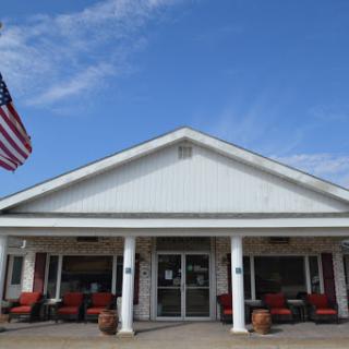 A welcoming entrance to a building featuring the American flag and outdoor seating.
