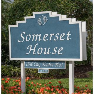 A sign for Somerset House surrounded by greenery and flowers.