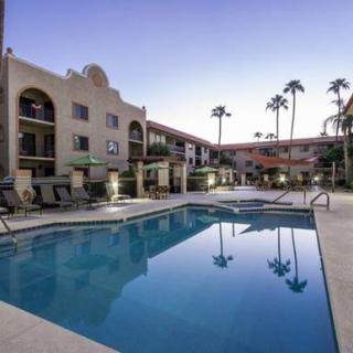 An outdoor swimming pool in a residential complex with palm trees at dusk.